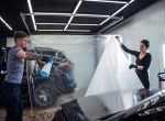 Team of technicians applying a protective film to a car, ensuring a flawless and durable finish for the vehicle exterior